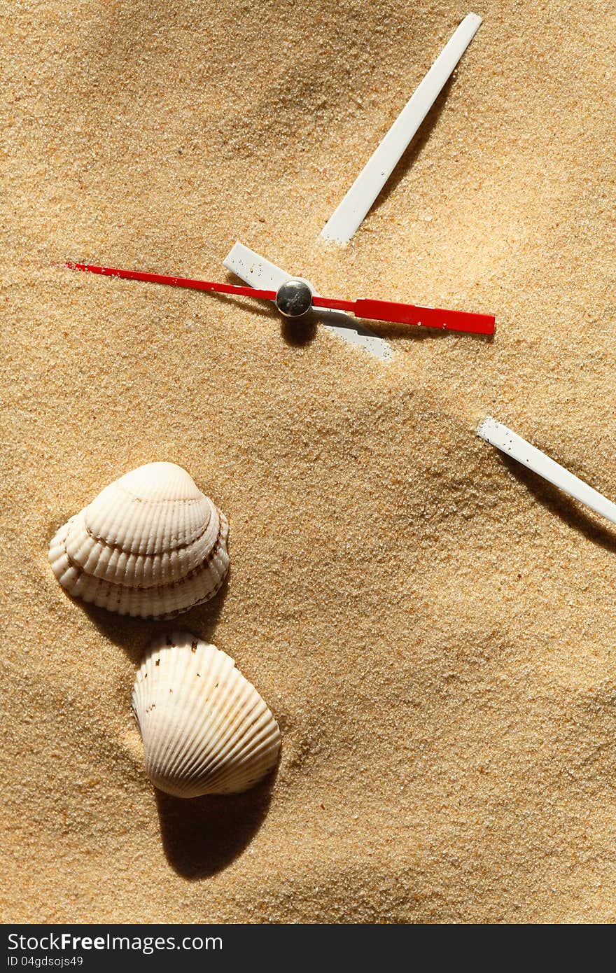 Time concept. Two seashells near clock hands on sand surface. Time concept. Two seashells near clock hands on sand surface