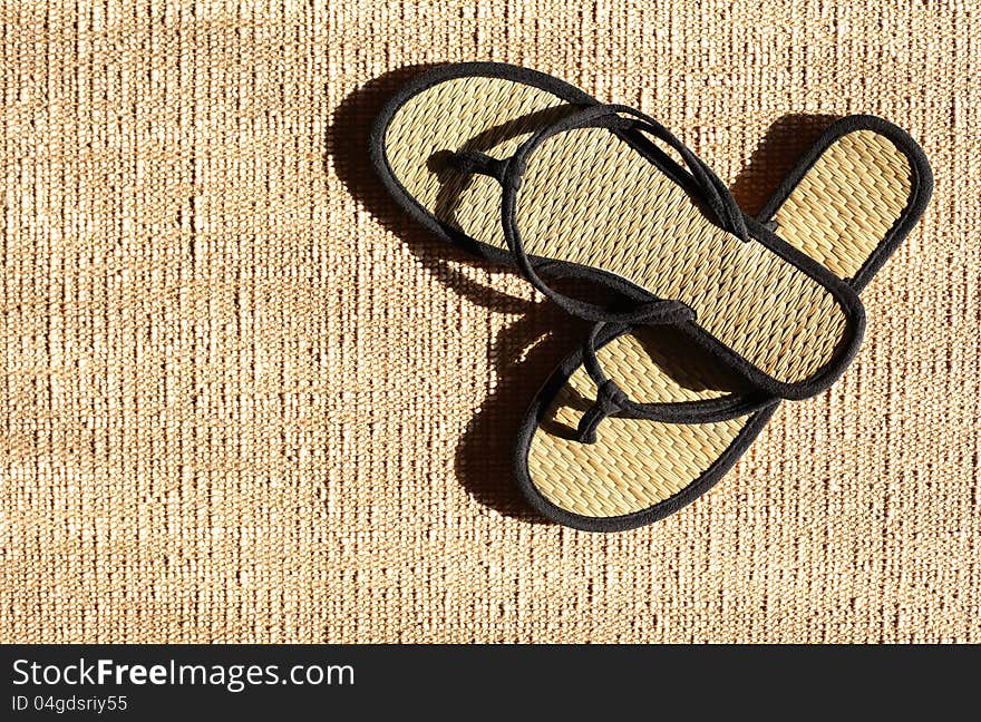 Pair of female summer thongs on jute surface under sunbeam. Pair of female summer thongs on jute surface under sunbeam