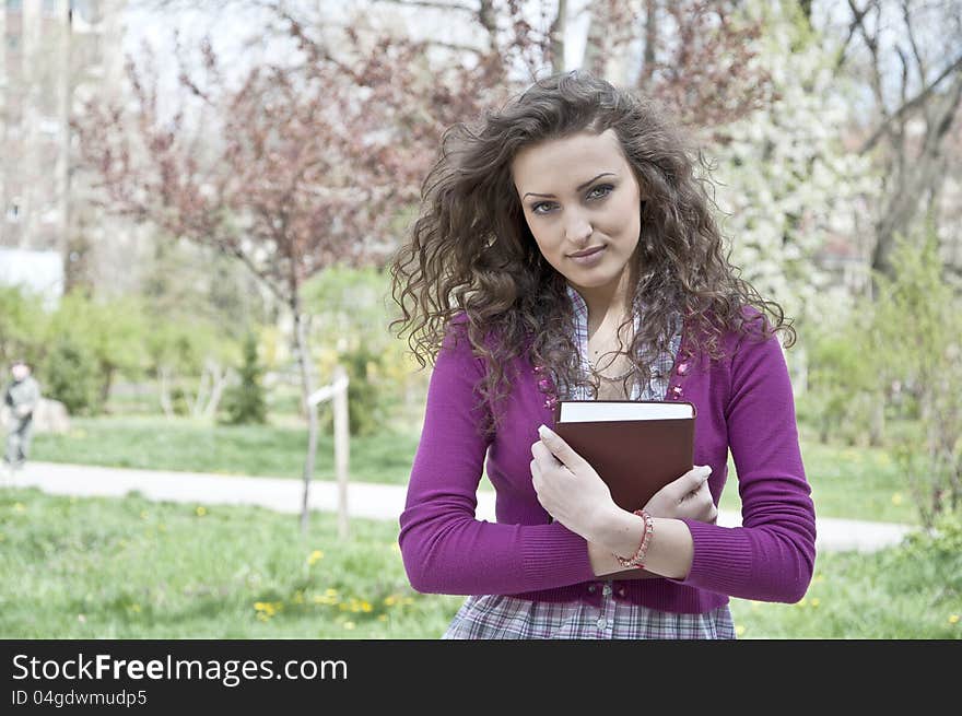 Young woman in park holding a book. Young woman in park holding a book