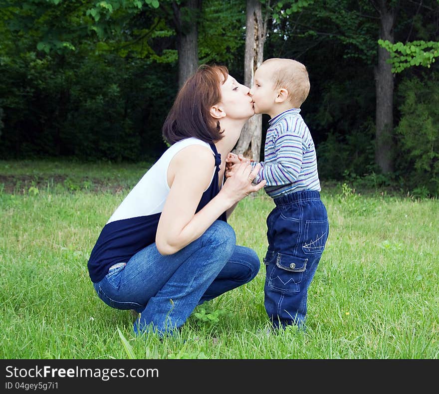 Mother kissing baby outdoors in the park. Mother kissing baby outdoors in the park