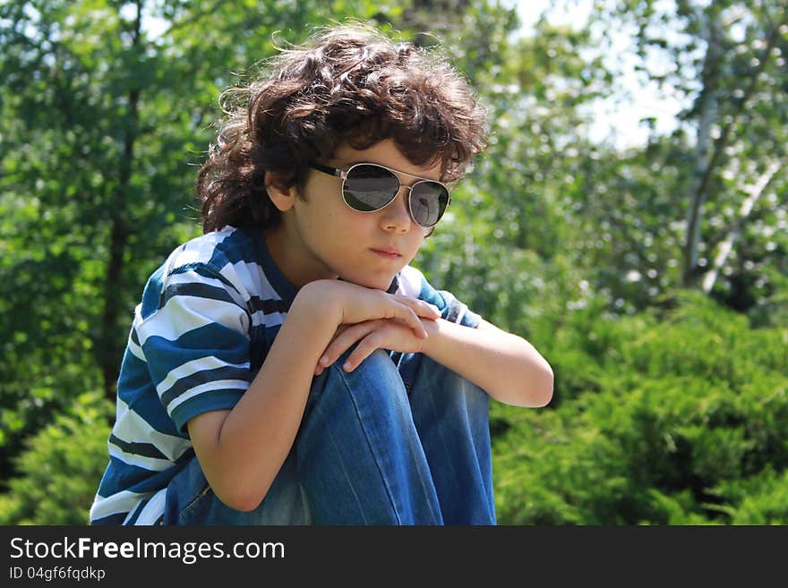 Portrait of a beautiful curly boy sitting with head propped on his knees. Portrait of a beautiful curly boy sitting with head propped on his knees