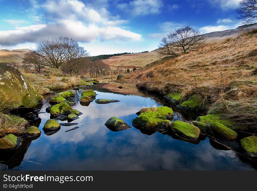 A beautiful landscape with blue sky and green stones in the foreground. This landscape is near dovestone reservoir in the Peak District. A beautiful landscape with blue sky and green stones in the foreground. This landscape is near dovestone reservoir in the Peak District.