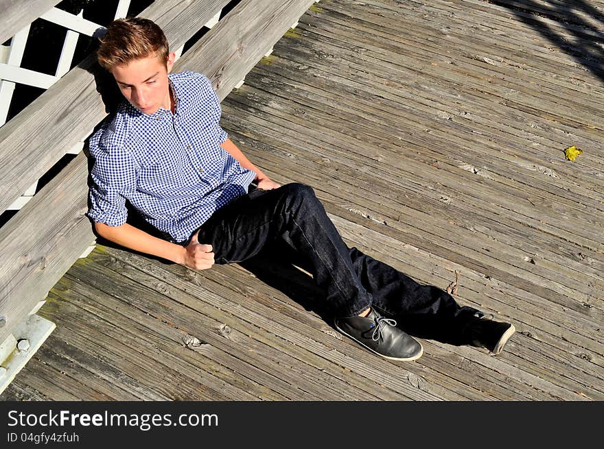 Teenager Sitting Along The Side Of A Bridge