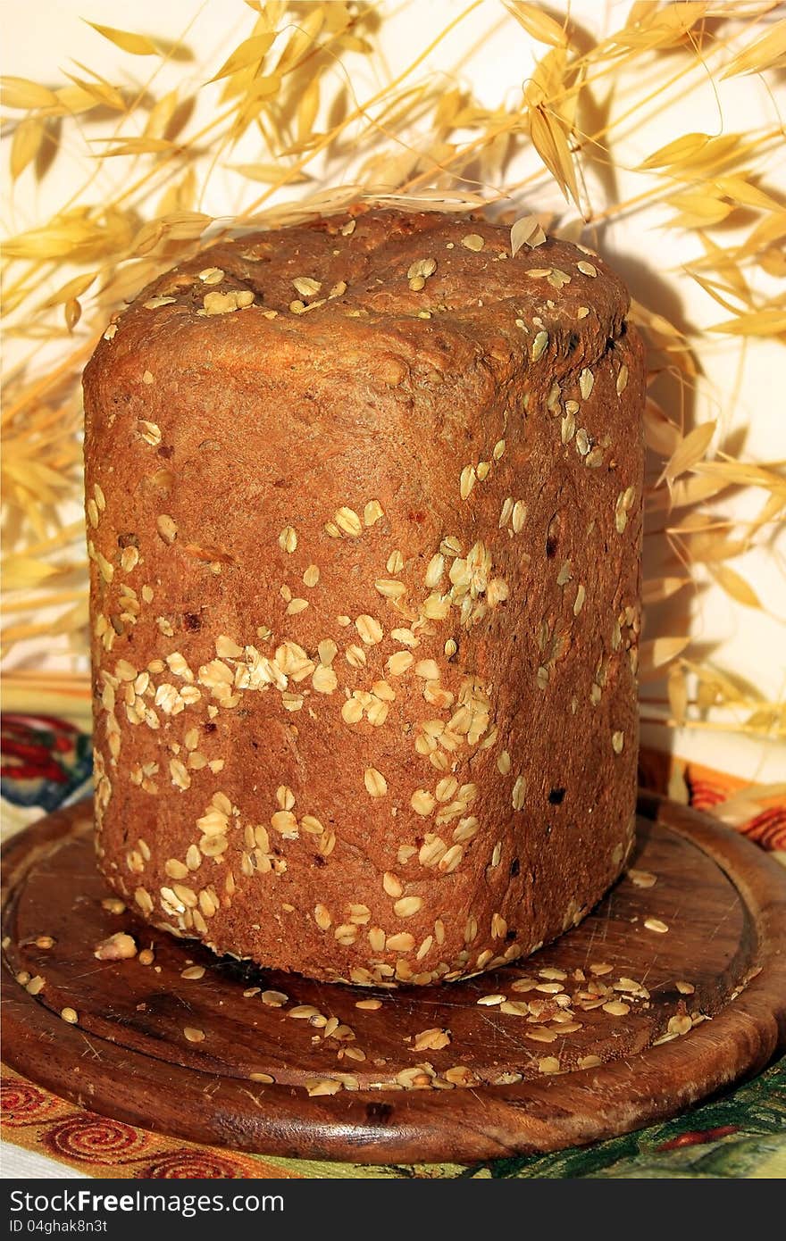 Freshly baked homemade bread on a wooden tray. on the background ears of oats