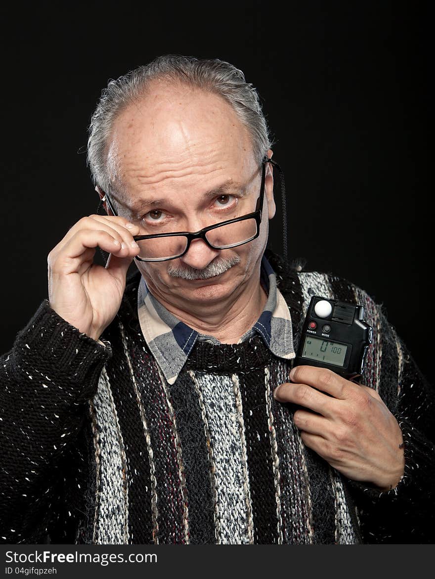 Portrait of a senior photographer with a flash meter and glasses