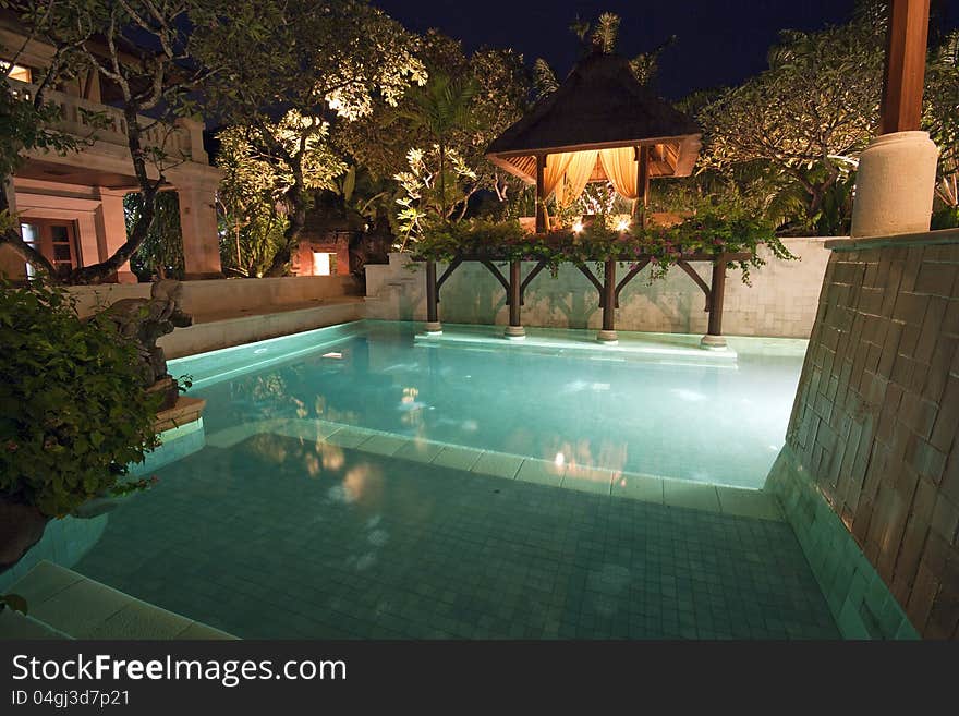 Unoccupied and lit swimming pool in Bali in dusk.