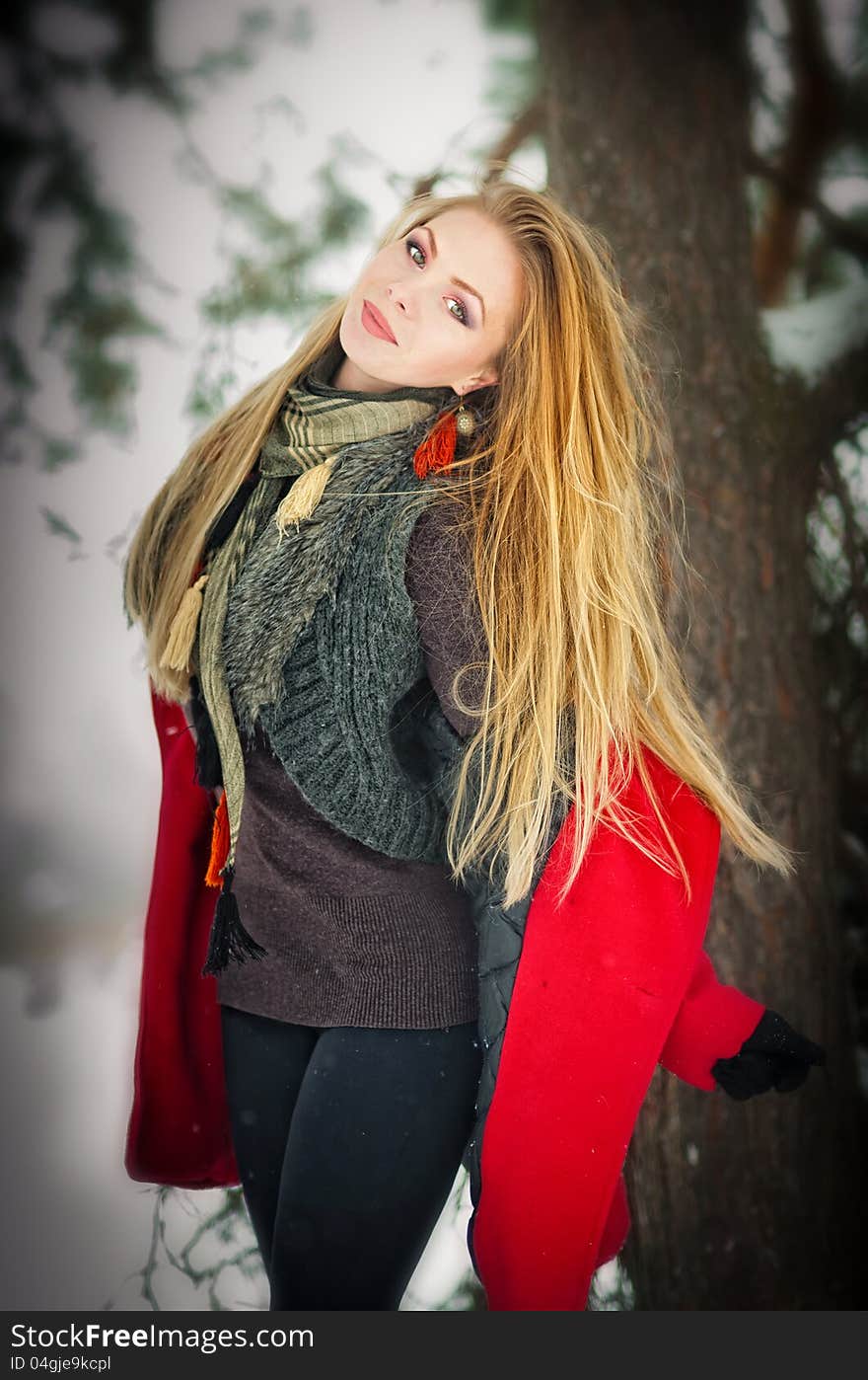 Blonde girl with red coat in winter snow