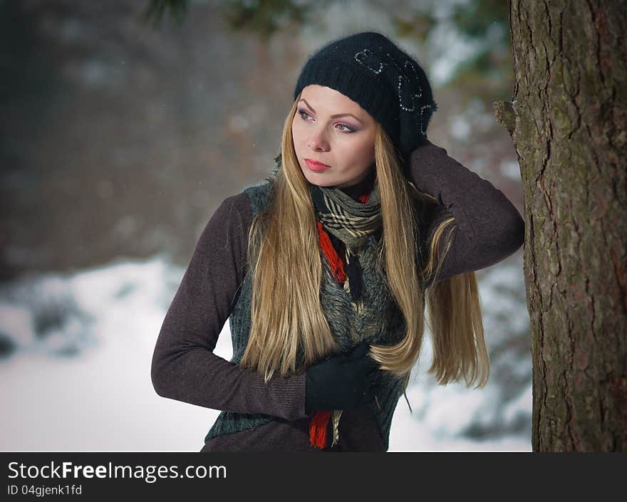 Pretty blonde girl with black cap play in winter snow