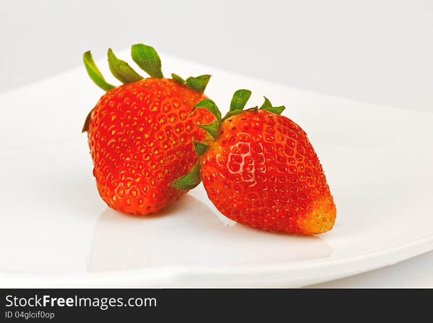 Two berries of strawberry on a white plate