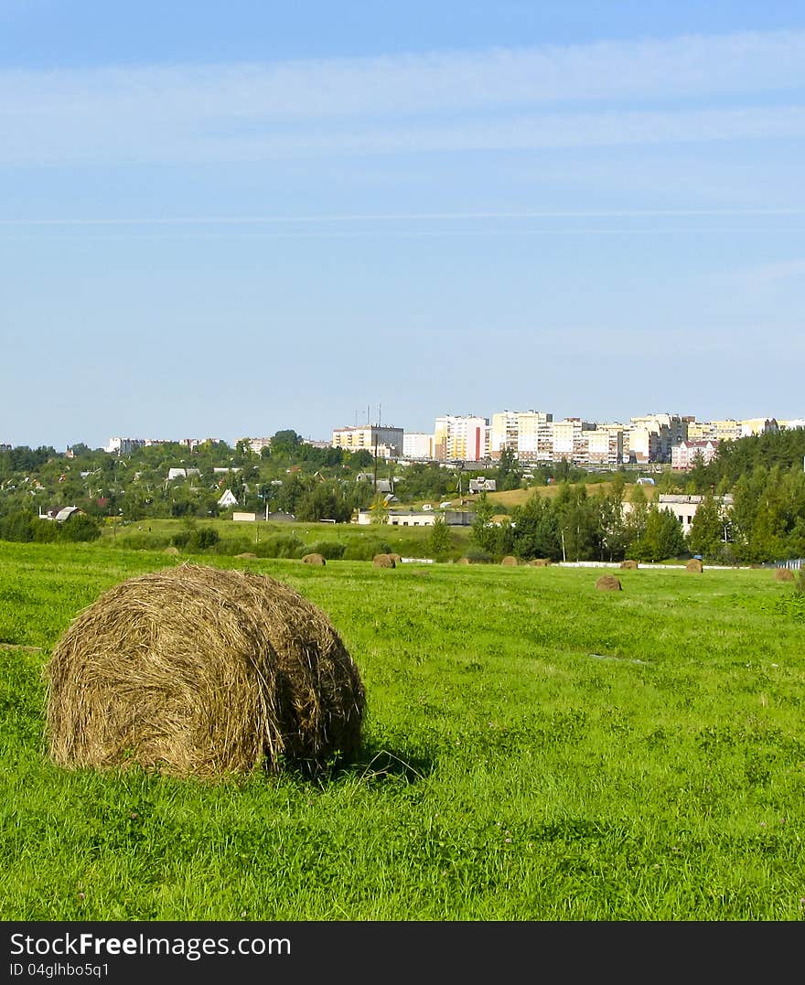 Summer haymaking. A haystack against a city.