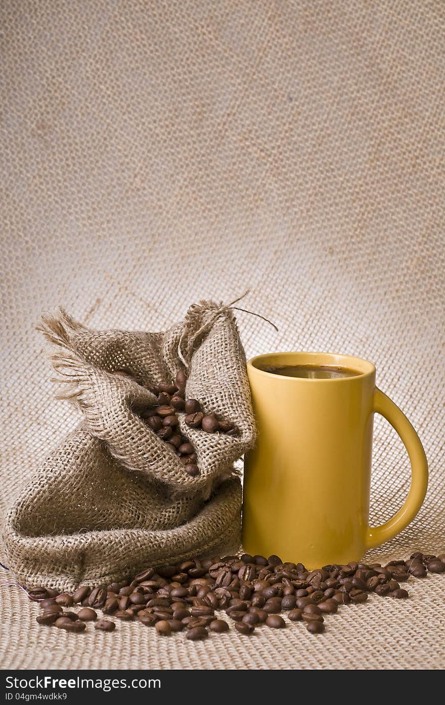 Cup of coffee with beans and sack over brown burlap background. Cup of coffee with beans and sack over brown burlap background