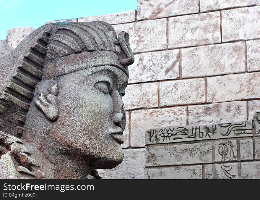 Sphinx head closeup and Egyptian wall background