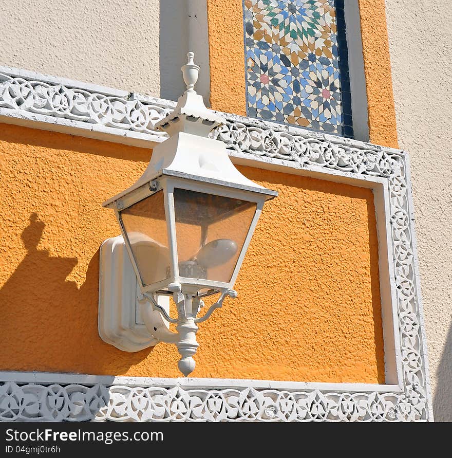 White street lamp with a very colorful north African traditional wall behind it. White street lamp with a very colorful north African traditional wall behind it