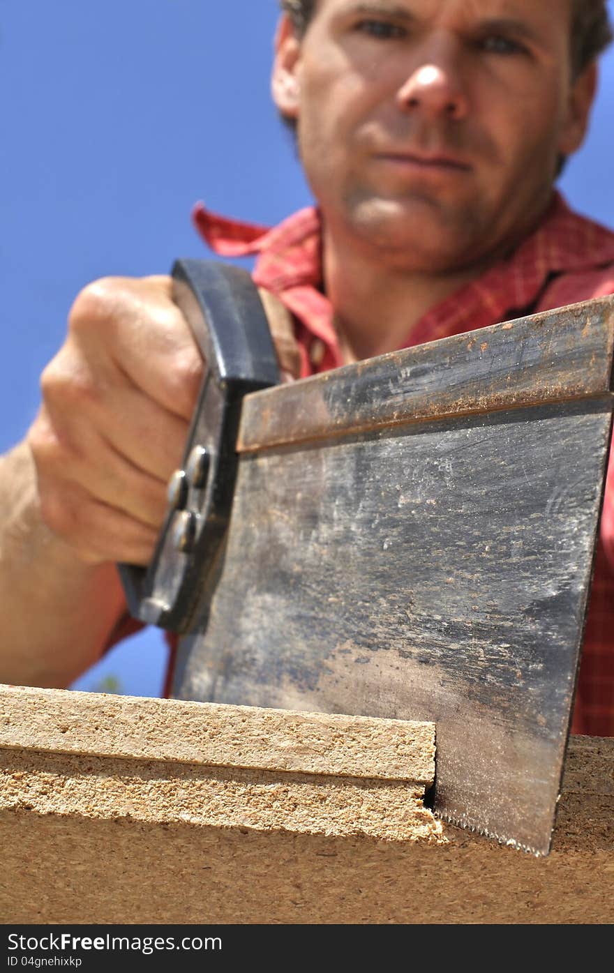 Inferior shot of hard working man sawing wood outdoors. Inferior shot of hard working man sawing wood outdoors