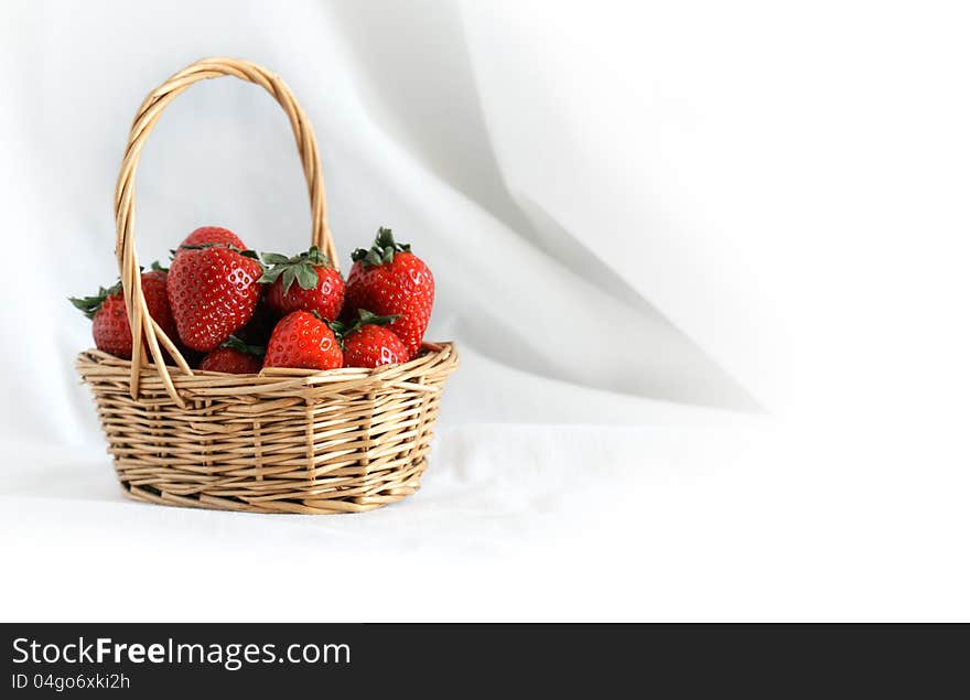 Nice wicker basket full of freshness red strawberry on white cloth background. Nice wicker basket full of freshness red strawberry on white cloth background