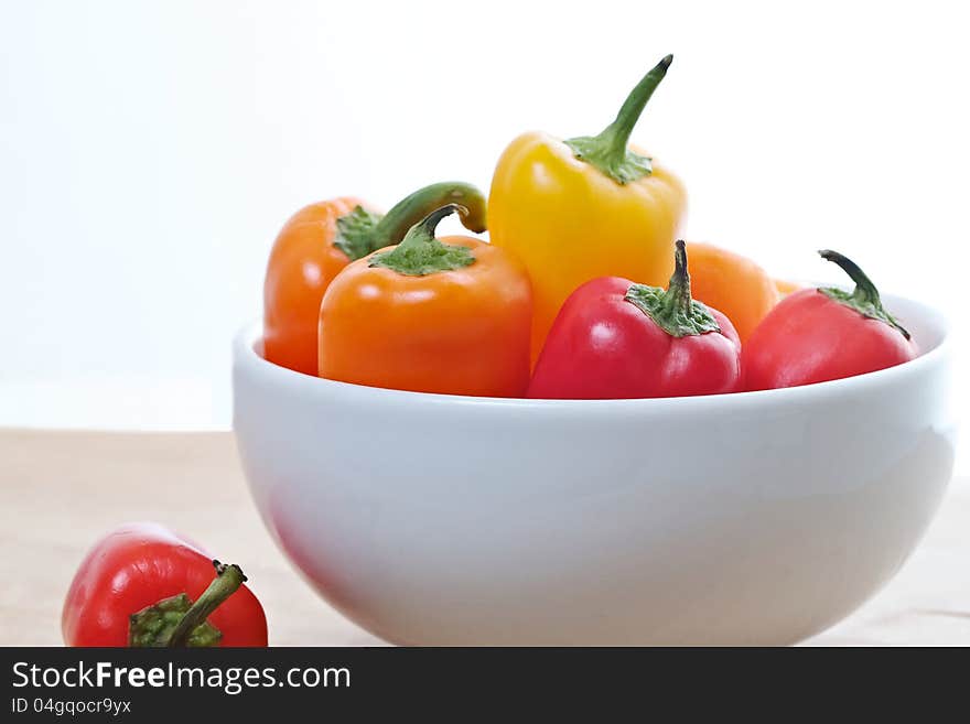 White bowl containing brightly colored mini sweet peppers. White bowl containing brightly colored mini sweet peppers