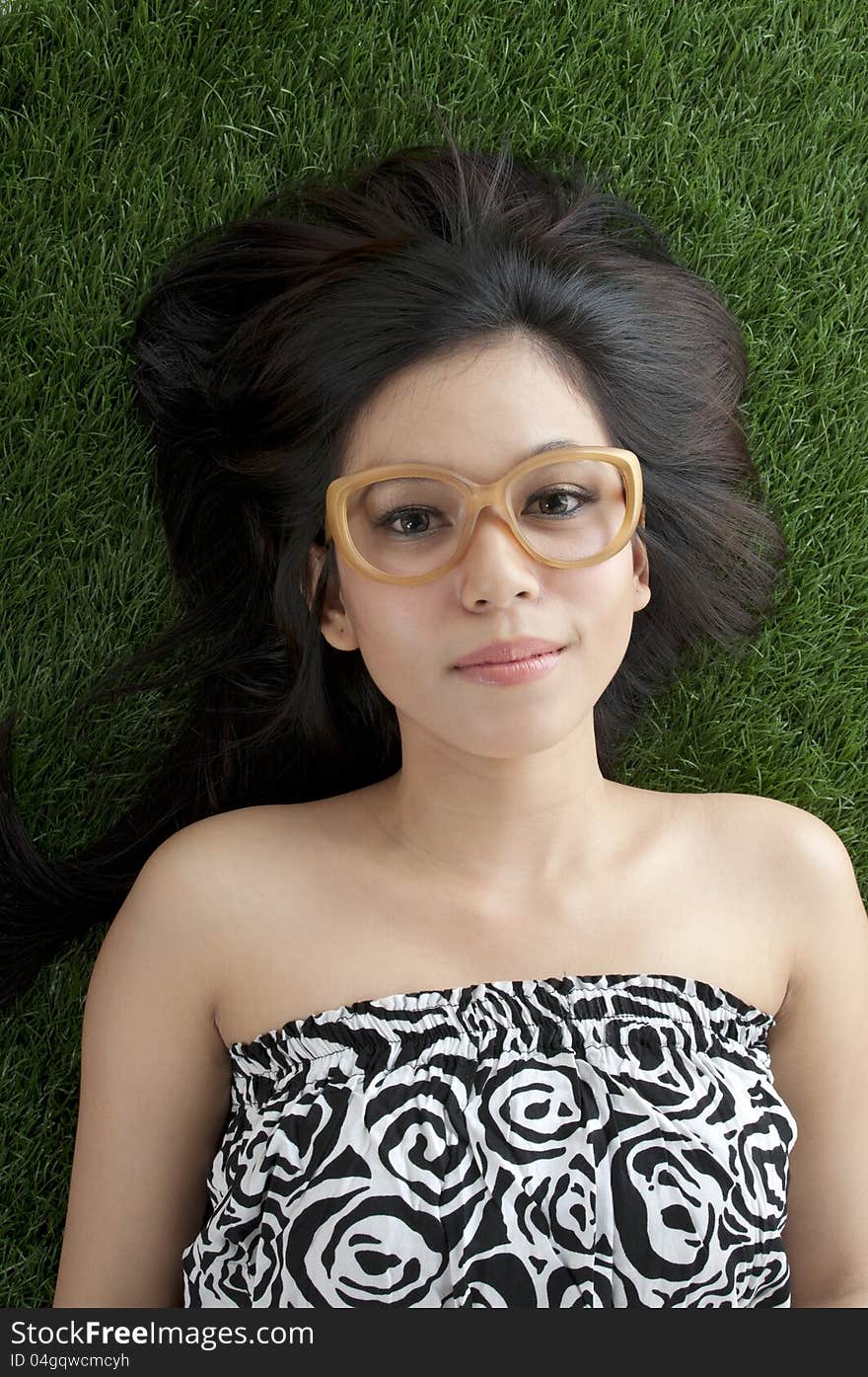 Cute asian girl laying on the green grass. Cute asian girl laying on the green grass