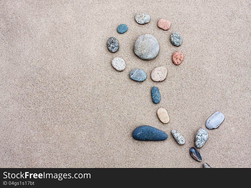 Pebbles were laid out on the sand in form of a flower. Pebbles were laid out on the sand in form of a flower