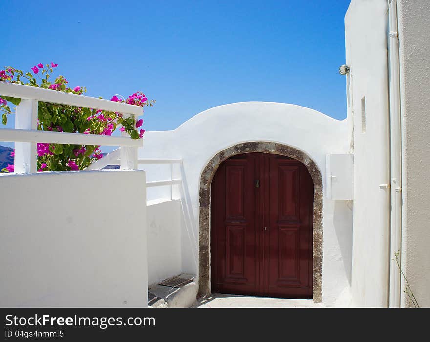 Santorini terrace with pink beautiful flowers and small doors