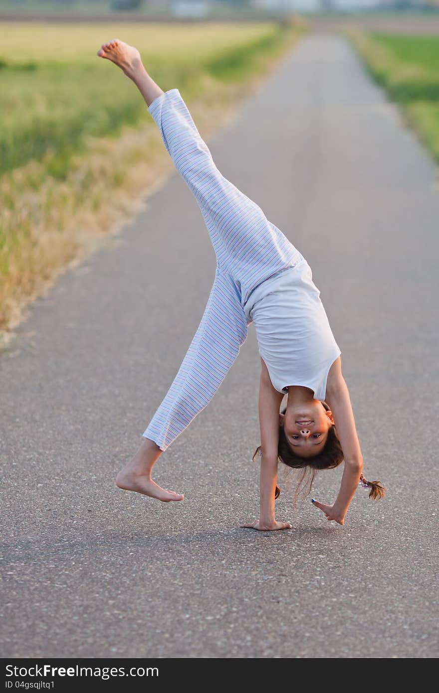 Young girl makes a cartwheel on a path