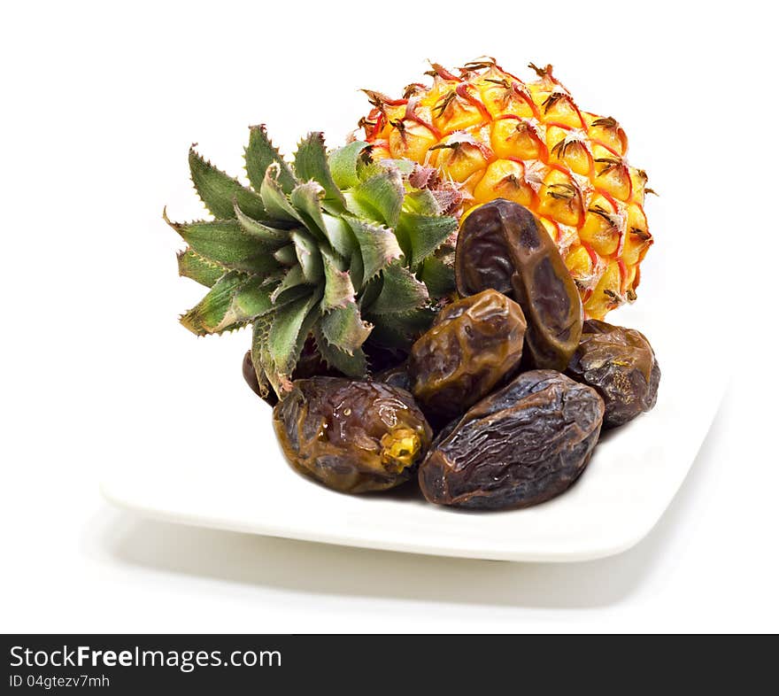 Ripe pineapple and dates on the white