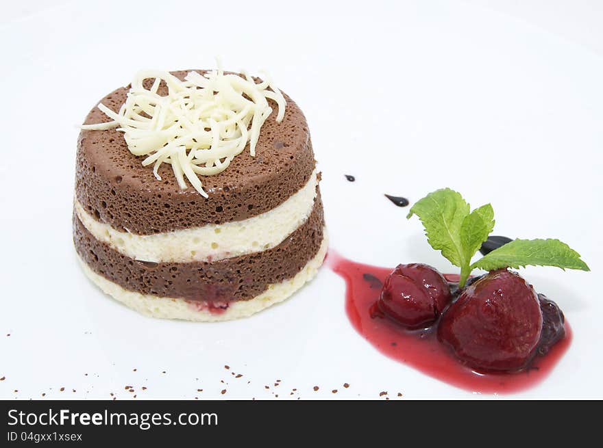 A piece of cream cake decorated with chocolate and mint. A piece of cream cake decorated with chocolate and mint