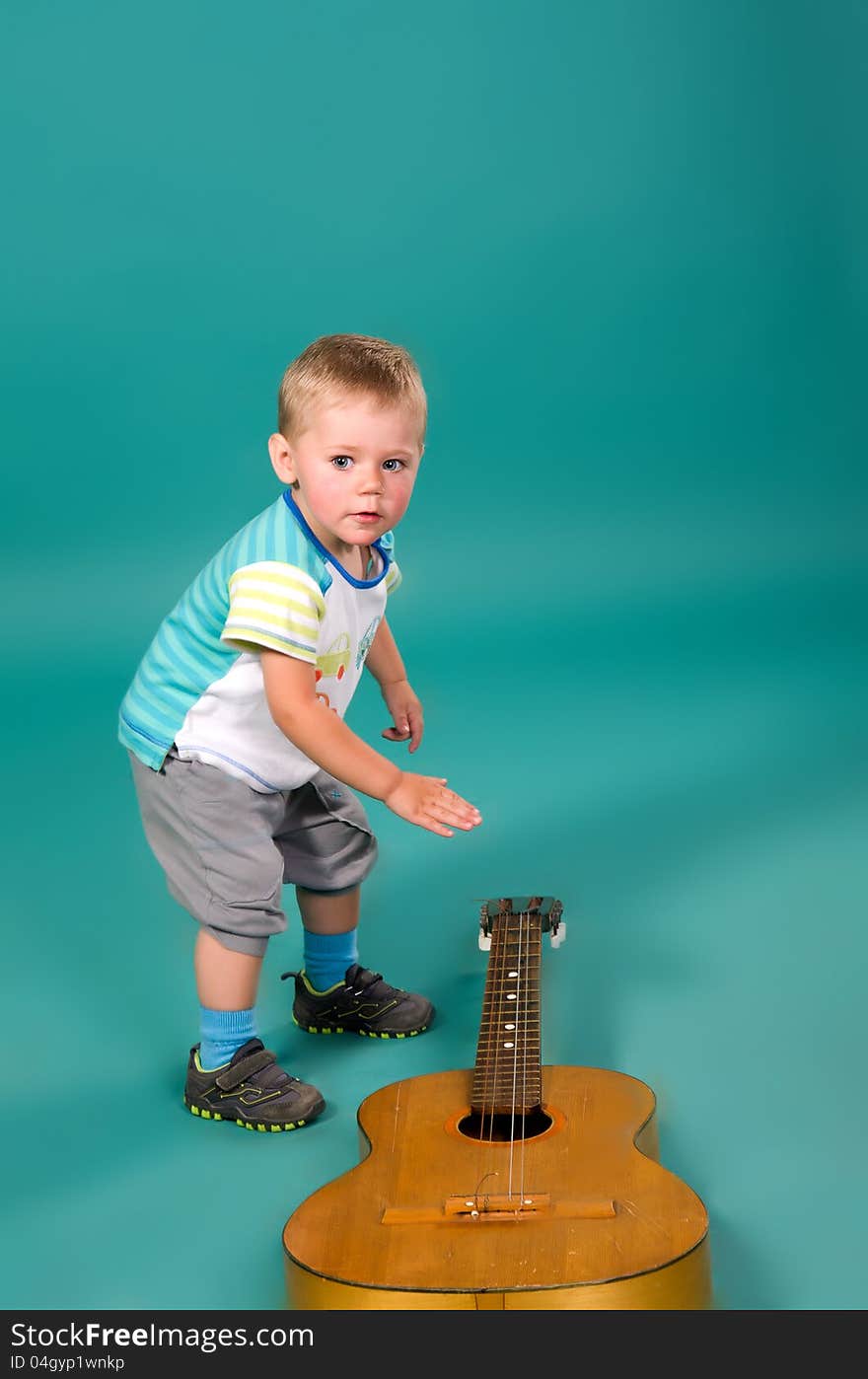 The boy reaches for the guitar, on a green background