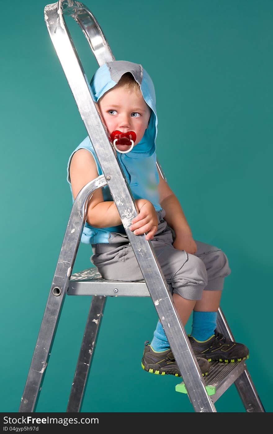 Boy sits on a ladder, in the hood