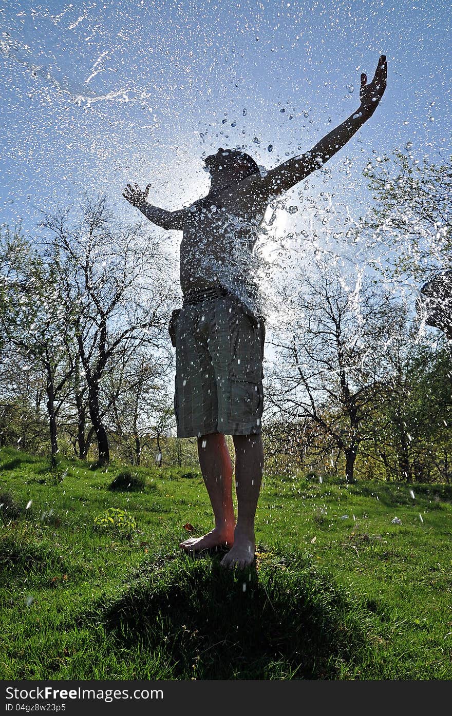 Young Man Enjoys The Water Splash In The Outdoors