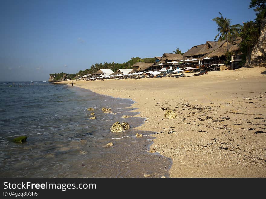 Sun chairs and buildings at a quiet beach in Bali.