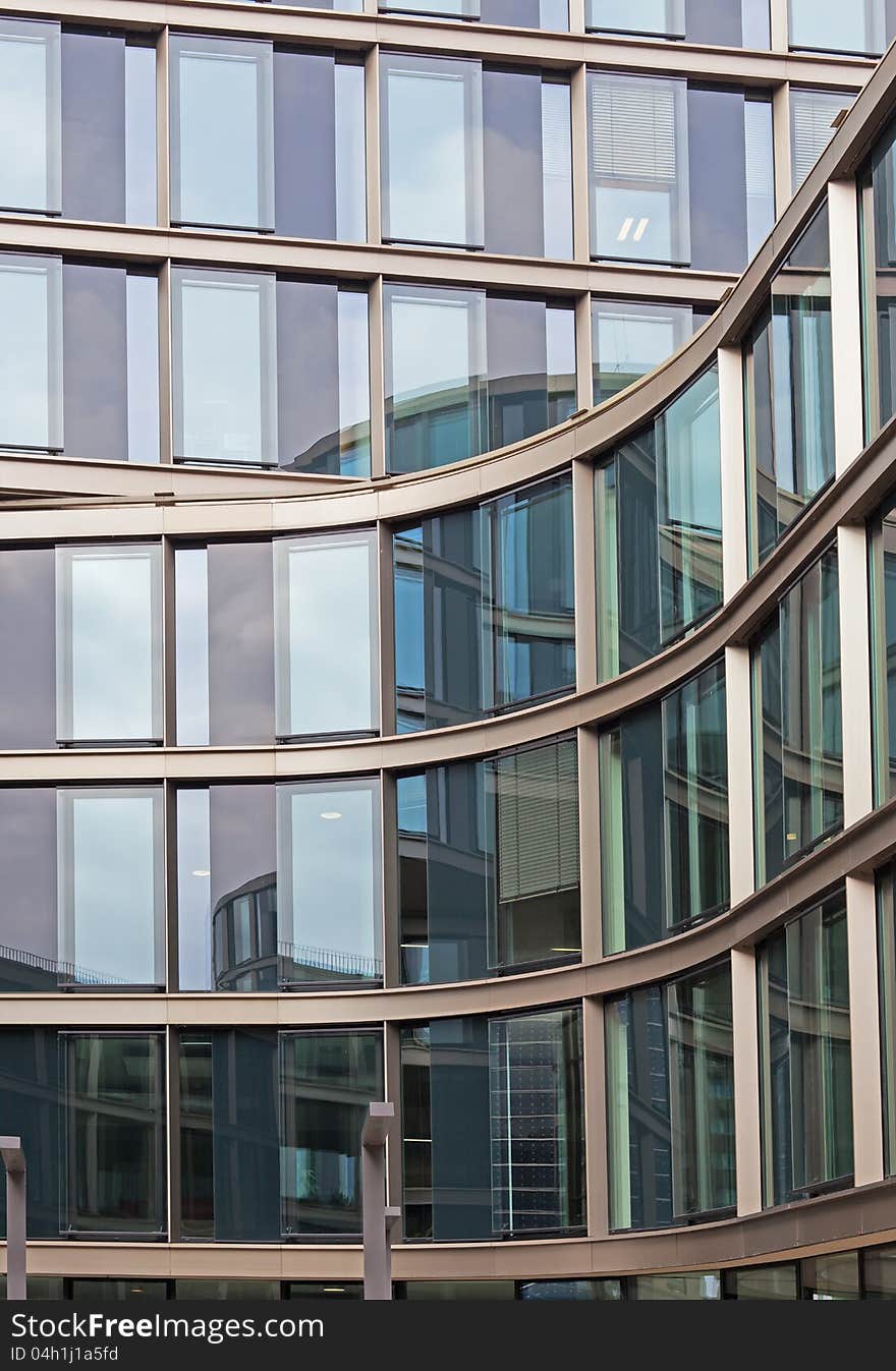 You see a modern building facade with building reflections in the city of Hamburg. You see a modern building facade with building reflections in the city of Hamburg.