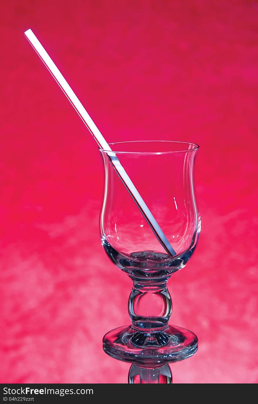 Empty glass with a straw on a red background