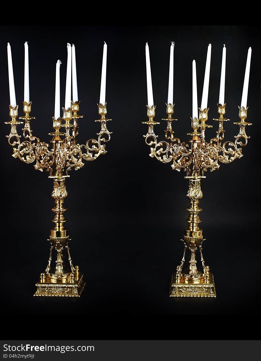 Two huge golden candleholder with white candles. Two huge golden candleholder with white candles.