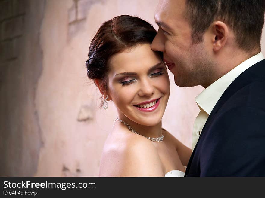 Groom kisses bride in stylish empty room. Groom kisses bride in stylish empty room