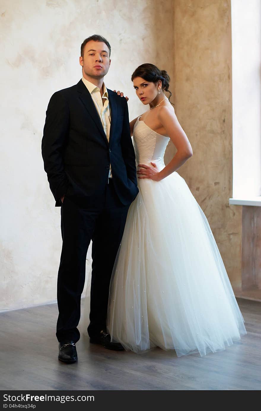 Bride and groom standing in empty room