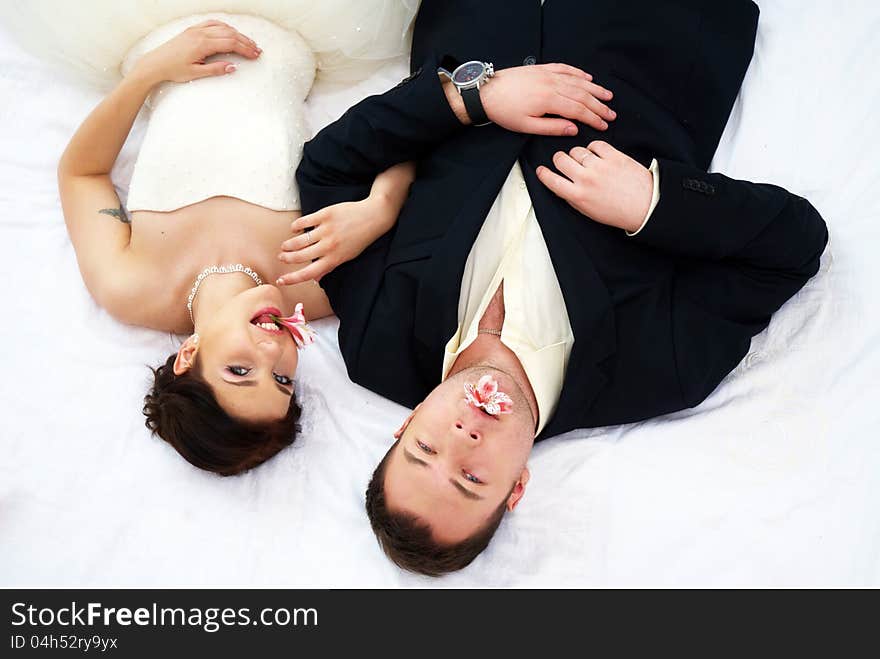 Bride and groom lying in bedroom with orchids