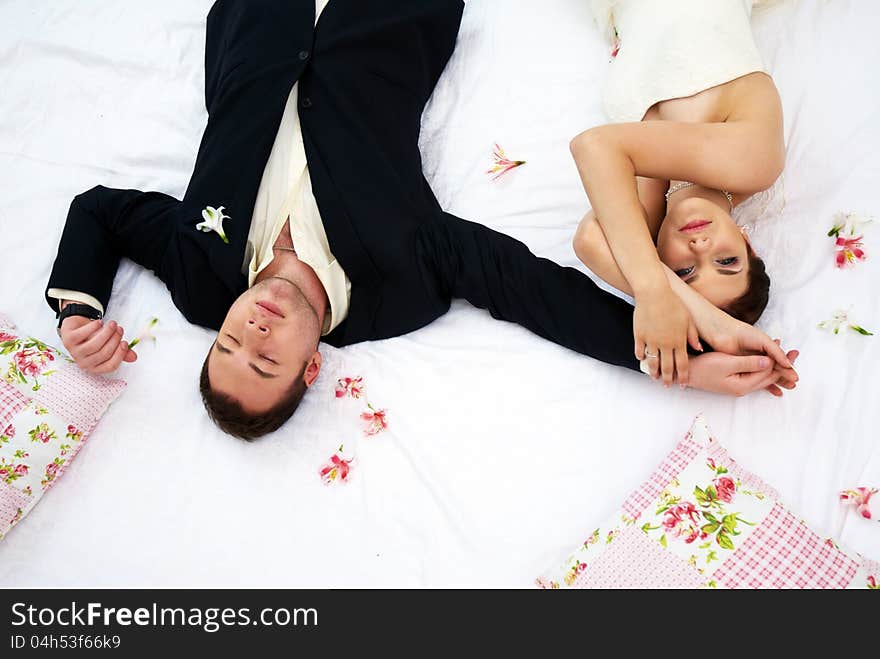 Bride and groom lying in bedroom with orchids