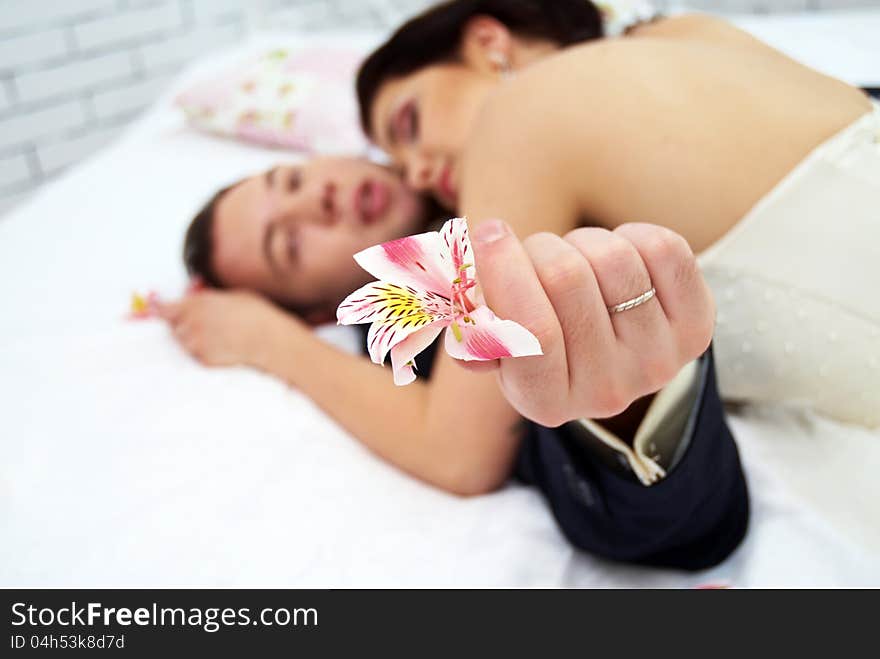 Bride and groom lying in stylish bedroom. orchid close up. Bride and groom lying in stylish bedroom. orchid close up