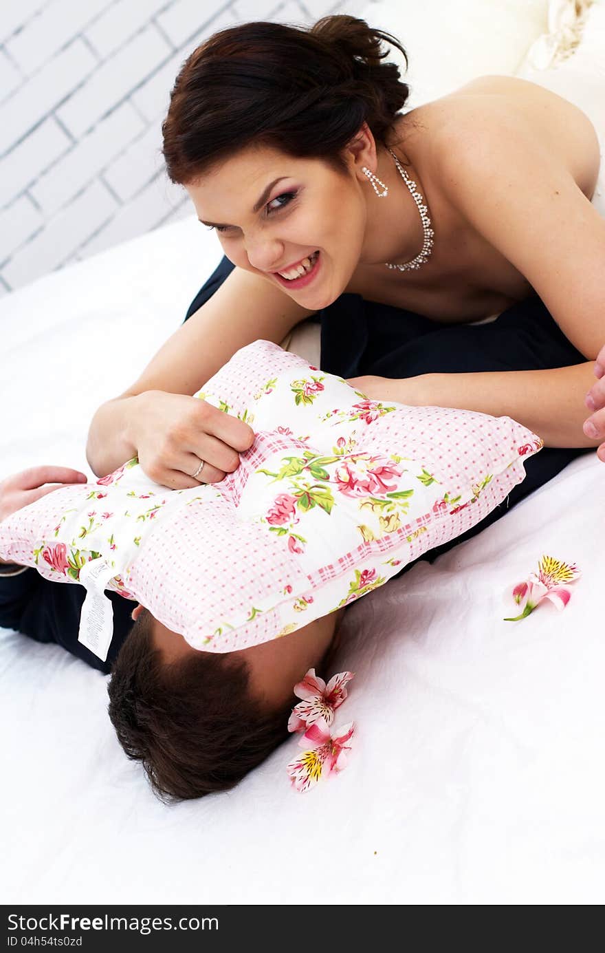 Bride and groom fooling in bedroom with orchids