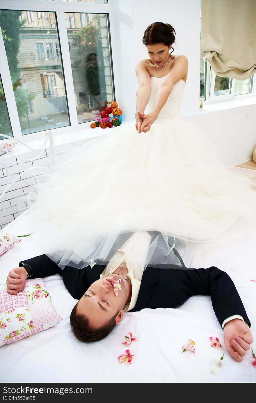 Bride and groom fooling in bedroom with orchids