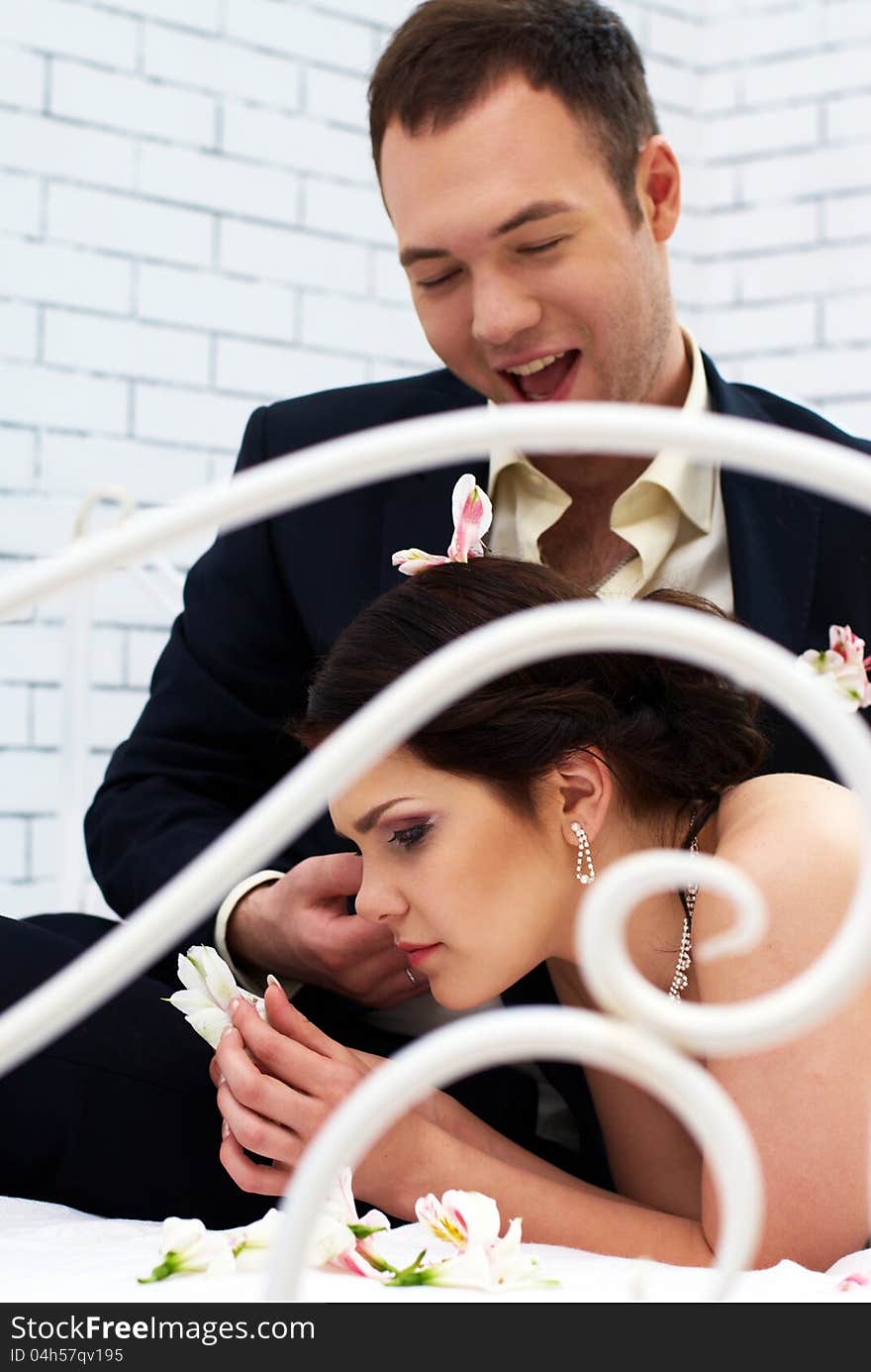 Bride and groom fooling in bedroom with orchids