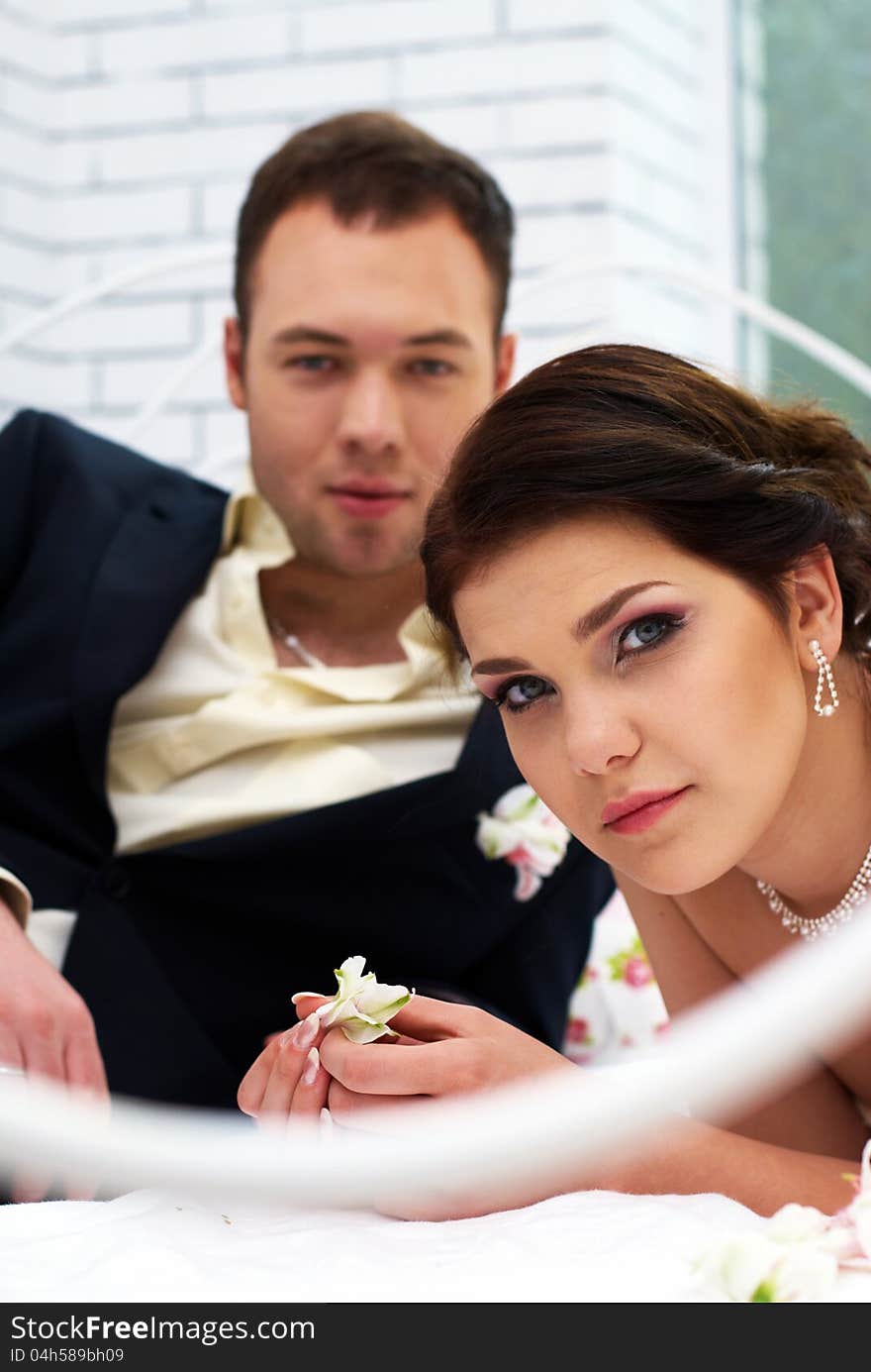 Bride and groom lying in stylish bedroom with orchids. Bride and groom lying in stylish bedroom with orchids