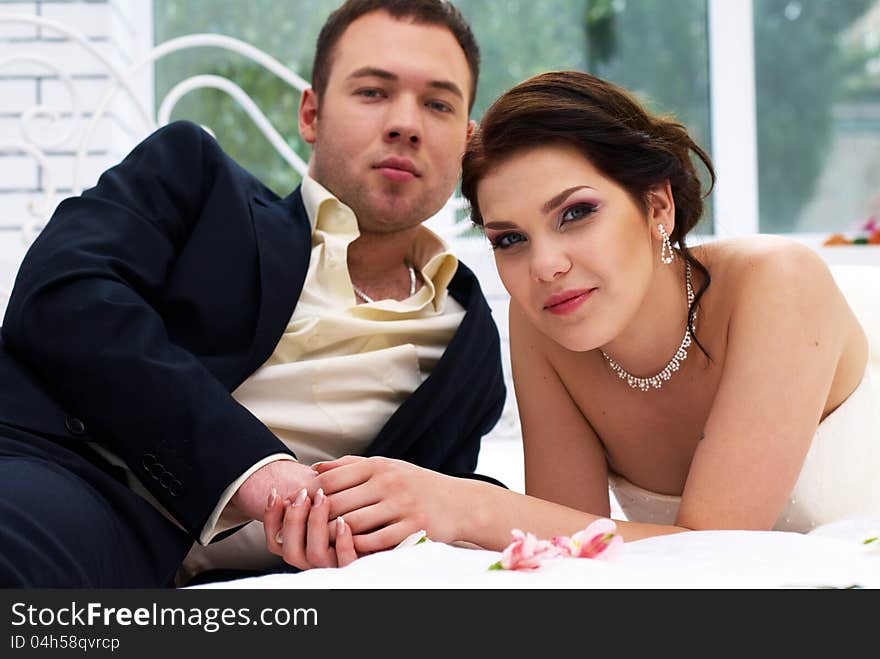 Bride and groom lying in bedroom with orchids