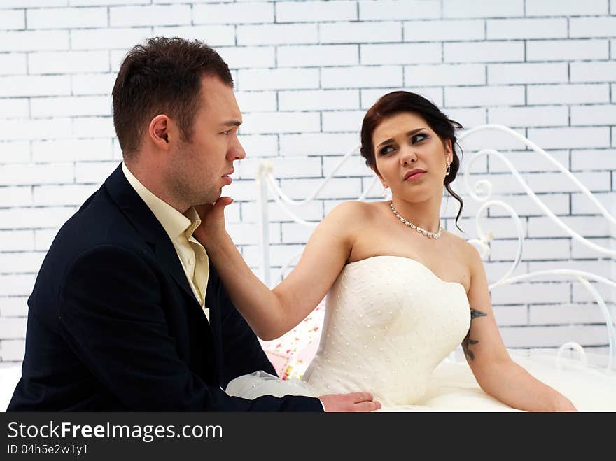 Bride and groom sitting on bed in bedroom