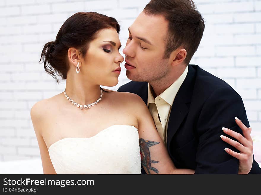 Groom Kisses Bride In White Room