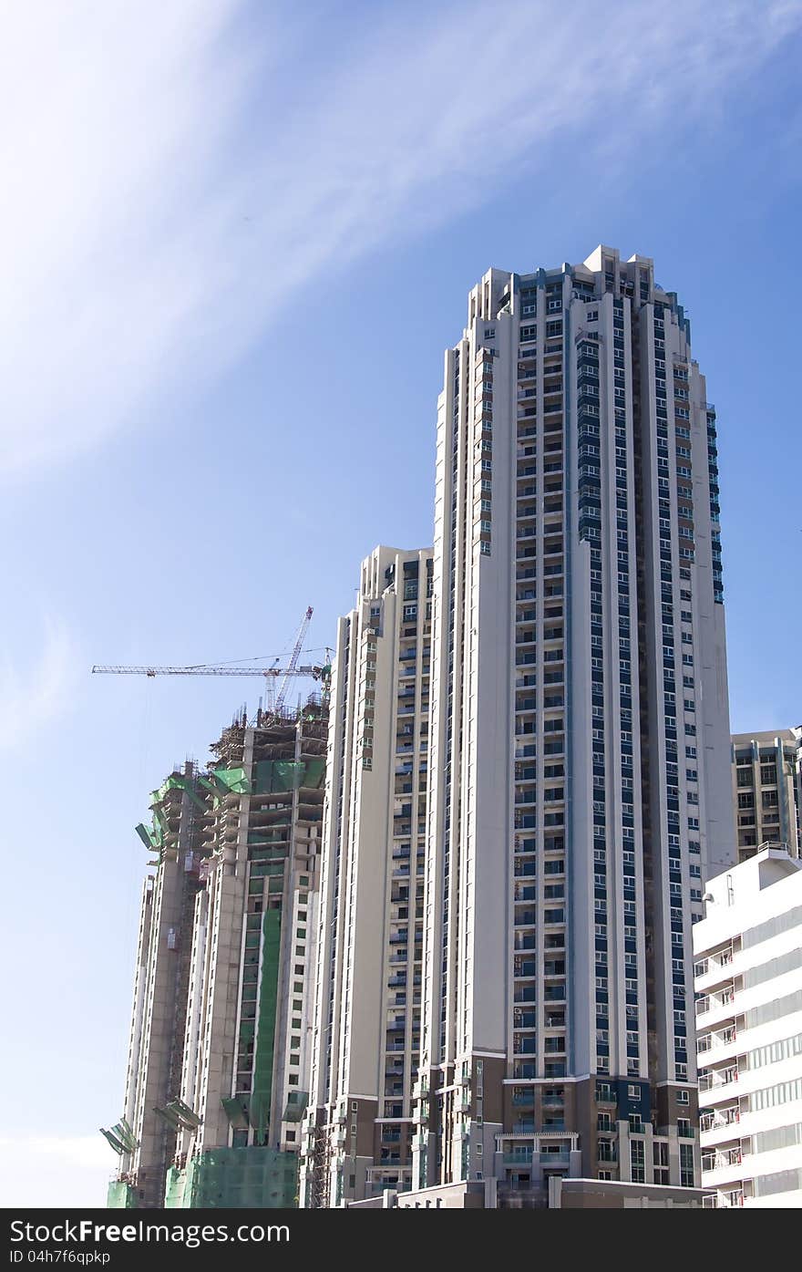 Buildings under construction and cranes under a blue sky