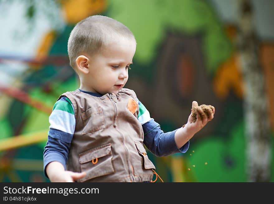 Small child plays with sand on hand