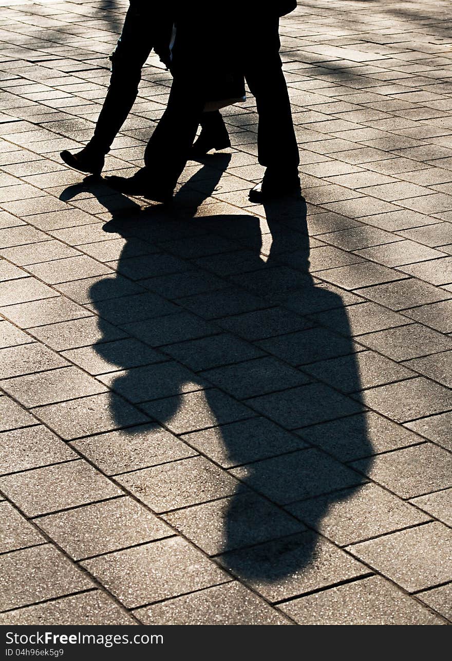 A shadow of two people walking through the city. A shadow of two people walking through the city.