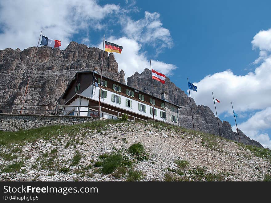 Mountain refuge with italian, french, german,austrian and UE flags, mountain and clouds in the background. Mountain refuge with italian, french, german,austrian and UE flags, mountain and clouds in the background