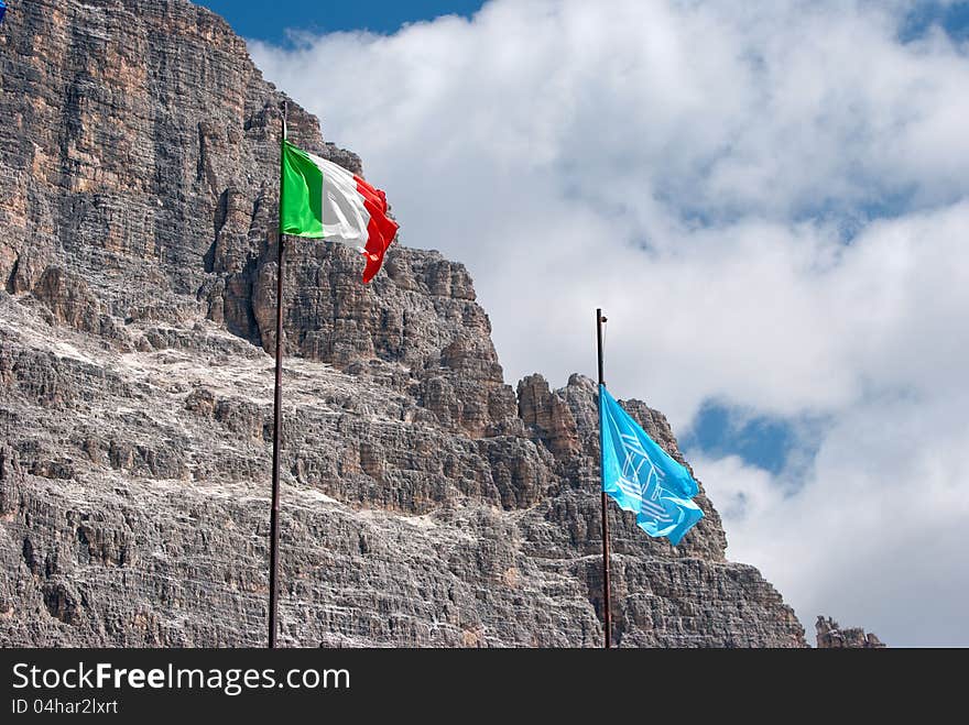 Italian and Unesco flags with mountain and clouds in the background